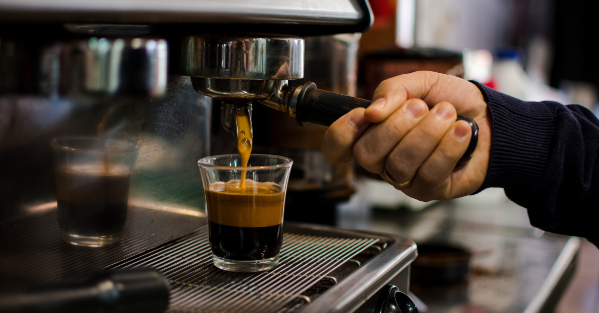 Barista pulling a fresh espresso shot into a glass cup using a professional espresso machine