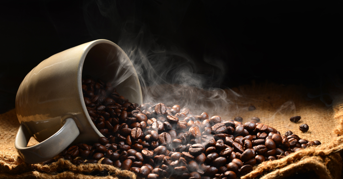 Steaming roasted dark coffee beans from a cup